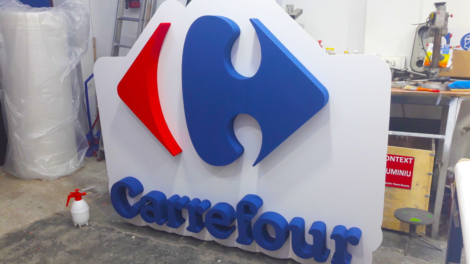 Litere volumetrice cu sigla Carrefour montate pe un panou alb